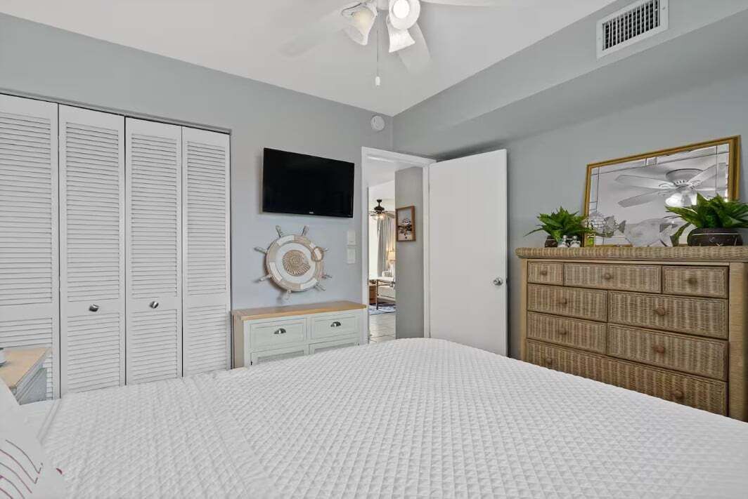 A bedroom with a bed, a dresser, a television, and a wardrobe.