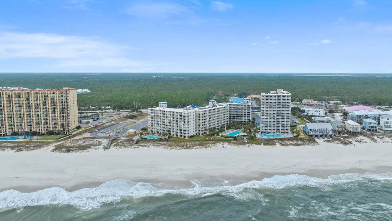 Un complexe hôtelier situé sur la côte, composé de plusieurs bâtiments, avec une plage et une vue sur l’océan.