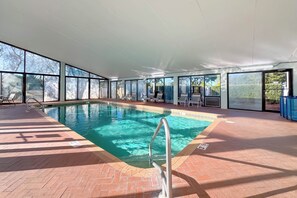 An indoor swimming pool with clear glass walls, a tiled floor, and a metal pool ladder. - Seaside Beach & Racquet Club 3503 | Beachfront, Pools, Tennis, Fitness | Beach Getaways (Orange Beach)