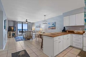 A modern kitchen with white cabinets, a wooden island, and a view to the outside. - Seaside Beach & Racquet Club 3503 | Beachfront, Pools, Tennis, Fitness | Beach Getaways (Orange Beach)