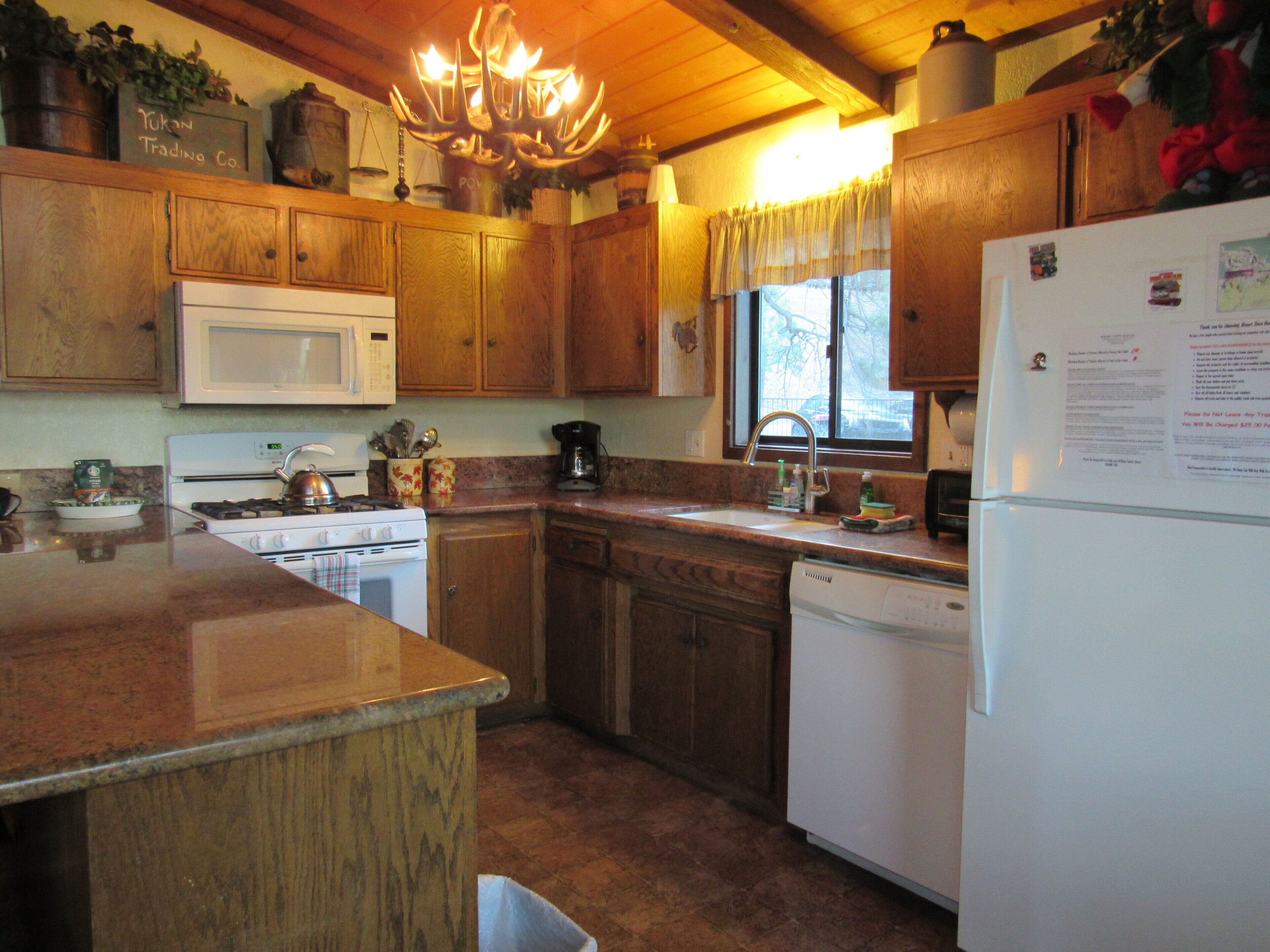 A kitchen with wooden cabinets, a stove, a microwave, and a refrigerator.