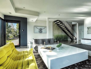A modern living room with a sofa, coffee table, and a staircase.