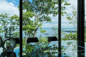 A room with a large window overlooking a body of water and trees.