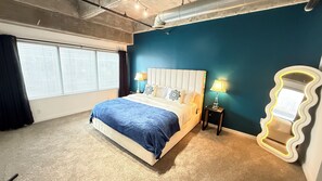 A bedroom with a bed, a nightstand, a mirror, and a window with blinds. - Spacious 3/3 bedrooms- Walk to Eats, Shops and Entertainment (Atlanta)