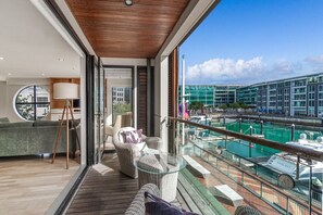 A balcony with a view of a marina, a sofa, a chair, and a floor lamp. - Gorgeous 2-Bed 2-Bath Harbour View Stunner (Auckland City)