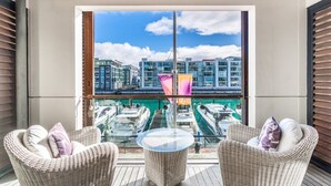 A balcony with wicker chairs, a glass table, and a view of boats and buildings. - Gorgeous 2-Bed 2-Bath Harbour View Stunner (Auckland City)