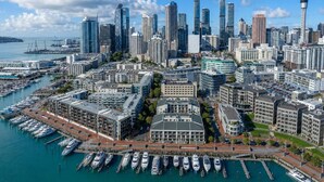 A cityscape with a prominent tower, a marina with boats, and high-rise buildings. - Gorgeous 2-Bed 2-Bath Harbour View Stunner (Auckland City)