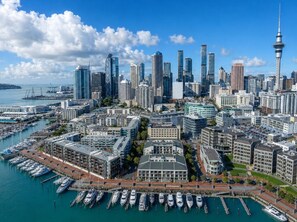 A cityscape with a prominent tower, a marina with boats, and high-rise buildings. - Gorgeous 2-Bed 2-Bath Harbour View Stunner (Auckland City)
