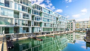 A modern hotel with a pool and a reflection of the building. - Luxury 2-Bed Marina Apartment Pool, Spa & Gym (Auckland City)