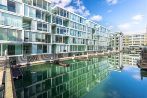 A modern hotel with a pool and a reflection of the building. - Luxury 2-Bed Marina Apartment Pool, Spa & Gym (Auckland City)