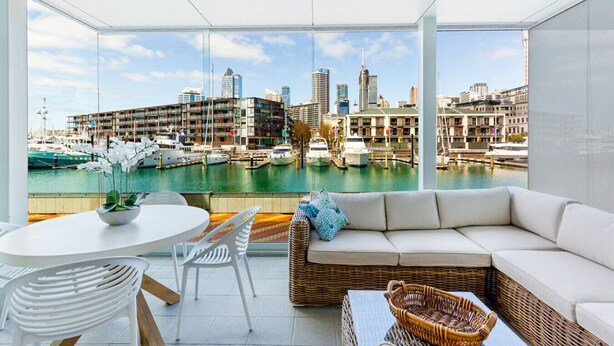 A modern living room with a view of a marina and city skyline. - Luxury 2-Bed Marina Apartment Pool, Spa & Gym (Auckland City)