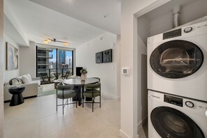 Ein modernes Apartment mit Essbereich, einer Couch, einem Tisch und einem großen Fenster mit Blick auf die Stadt.