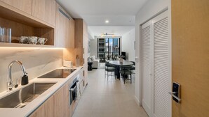 A modern kitchen with a built-in oven, a sink, and a dining area with a round table and chairs. - Crosby Miami WTC 1BR/1BA Cool Residence #2210 (Miami)