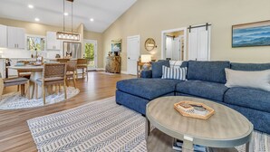 A spacious living area with a blue sofa, a round coffee table, and a dining area with wooden furniture. - Carolina Meadows w/ Hot tub (Weaverville)
