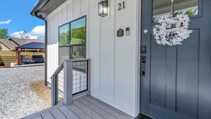 A house with a dark front door, a number '21' above it, a small porch with a railing, and a window. - Carolina Meadows w/ Hot tub (Weaverville)