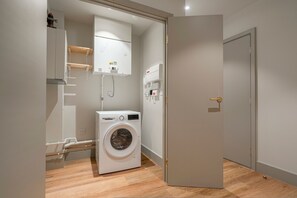 A compact laundry room with a washing machine, a dryer, and a utility cabinet. - Modern City Elegance (London)