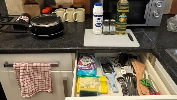 Una cucina dotata di forno a microonde, tagliere e diversi utensili da cucina.