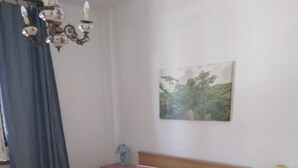 Et soveværelse med seng, et natbord, en lampe, et maleri og en lysekrone.