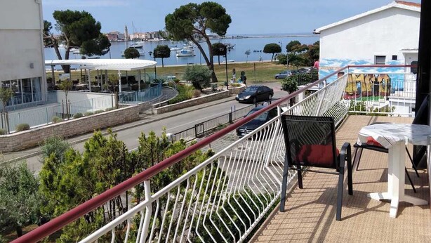 En balkon med udsigt over havet, et bord med stole og et gelænder.
