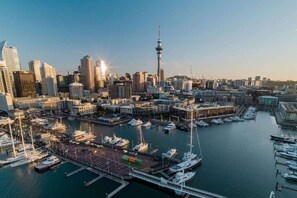 A cityscape with a prominent tower, marina with boats, and dense urban buildings. - Chic 1-Bed Apartment with Secure Parking (Auckland City)