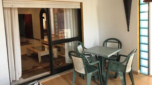 A room with a sliding glass door leading to another space, a table with chairs, and a decorative wall piece. - 2-bedroom Quarteira apartment near the beach. (Quarteira)