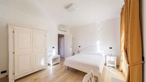 Ein Schlafzimmer mit einem Bett, Nachttischen, einem Kleiderschrank und einem Sessel.