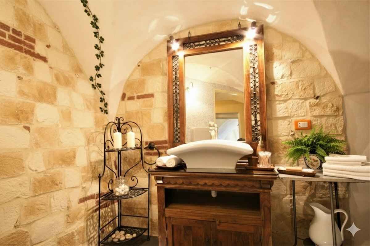 A bathroom with a stone wall, a wooden vanity, a mirror, and a shelf with toiletries.