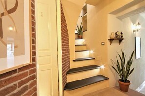 Eine Treppe mit einer Ziegelwand, einem Blumentopf und einem Regal mit Dekorationen.