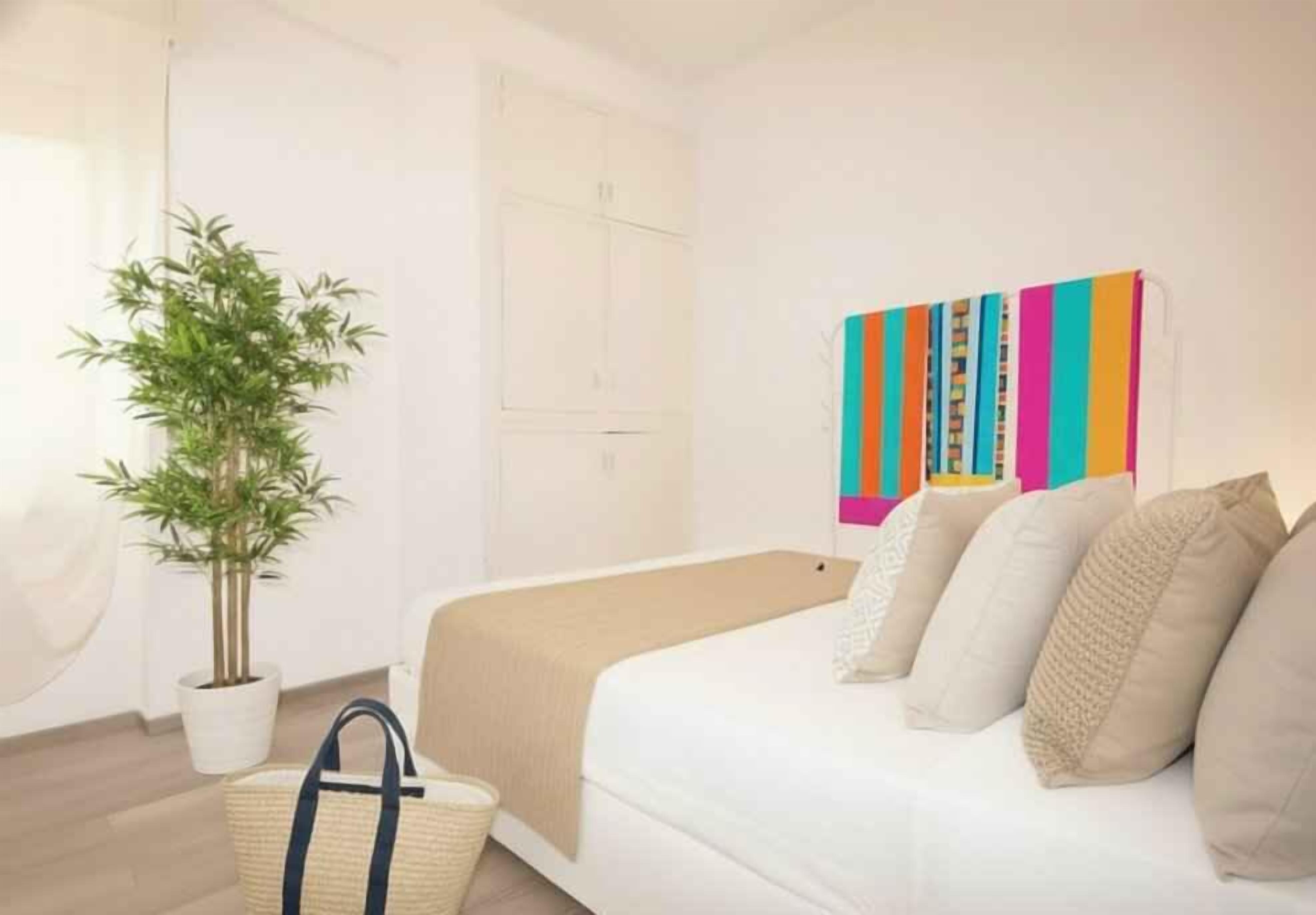 Una camera da letto con un letto, una pianta in vaso, un'opera d'arte colorata e un cesto di vimini.