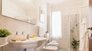 Een badkamer met een groot wastafel, een spiegel, een douche en een raam.