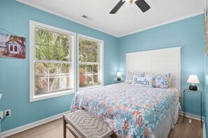 A bedroom with a bed, two bedside tables with lamps, a ceiling fan, and a window with blinds. - 7031 Lobster Lane - Golf Cart Included (Myrtle Beach)