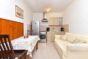 A compact kitchen with a dining table, a sofa, and a stove. - Holiday apartment with terrace and barbecue (Pula)