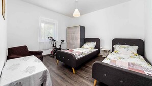 Ein Schlafzimmer mit zwei Betten, einem Tisch, einem Stuhl und einem Fahrrad.