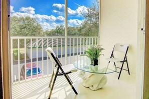 Ein Balkon mit zwei Stühlen, einem Glastisch und einem Blumentopf.
