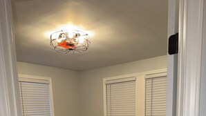 A bedroom with a bed, a nightstand, a lamp, and a ceiling light fixture.