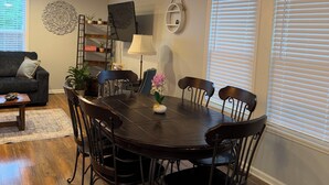 A dining area with a dark wooden table, black chairs, a ceiling fan, and a decorative wall piece.