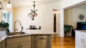 Una cocina con encimera de granito, electrodomésticos de acero inoxidable y un comedor con mesa y sillas.