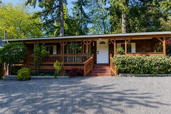 A lodge with a wooden exterior, a porch, and a gravel driveway.