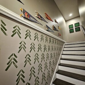 A staircase with a wall featuring state flags and a pattern of arrows. - Bunk/Game Room, Near Lake, Pet Friendly, Firepit, FUN! (Toccoa)