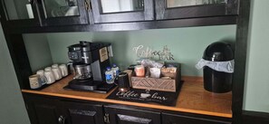Un espacio para café con una cafetera Keurig, tazas, un molinillo de café y un letrero de estación de café.