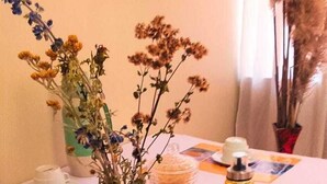 Una mesa dispuesta con vajilla blanca, un florero de vidrio con flores secas y un adorno.