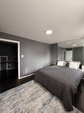Un dormitorio con una cama grande, un espejo y una puerta que da a otra habitación.