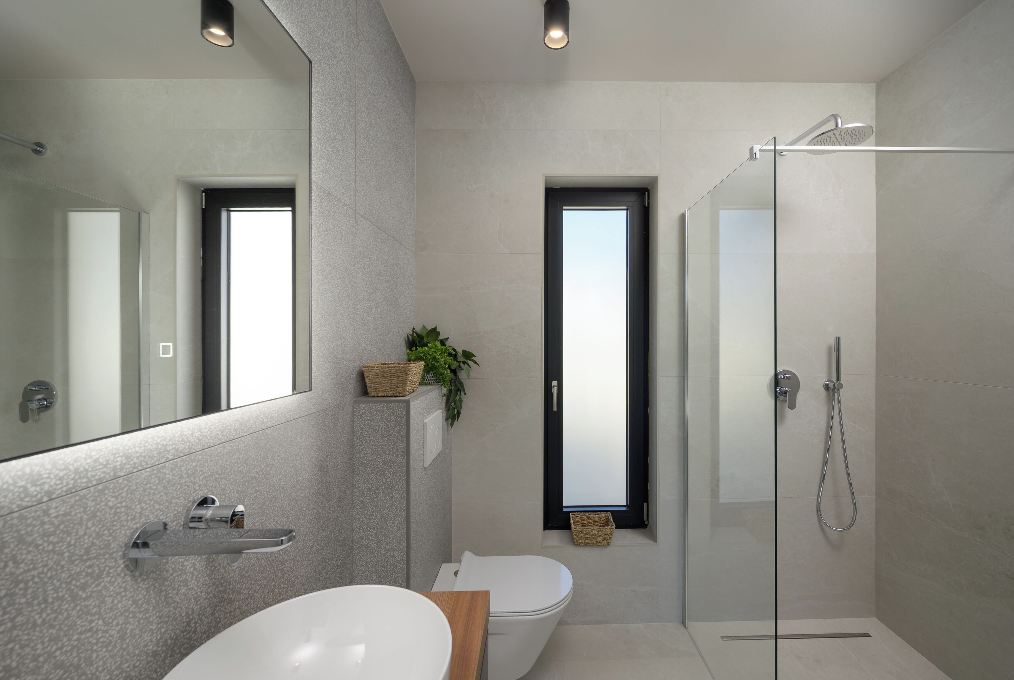 A modern bathroom with a glass-enclosed shower, a white sink, and a large mirror.