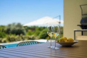 A table with two wine glasses and a bowl of lemons, overlooking a pool and greenery. - Villa Modrić (Istria - Pazin) (Pazin)