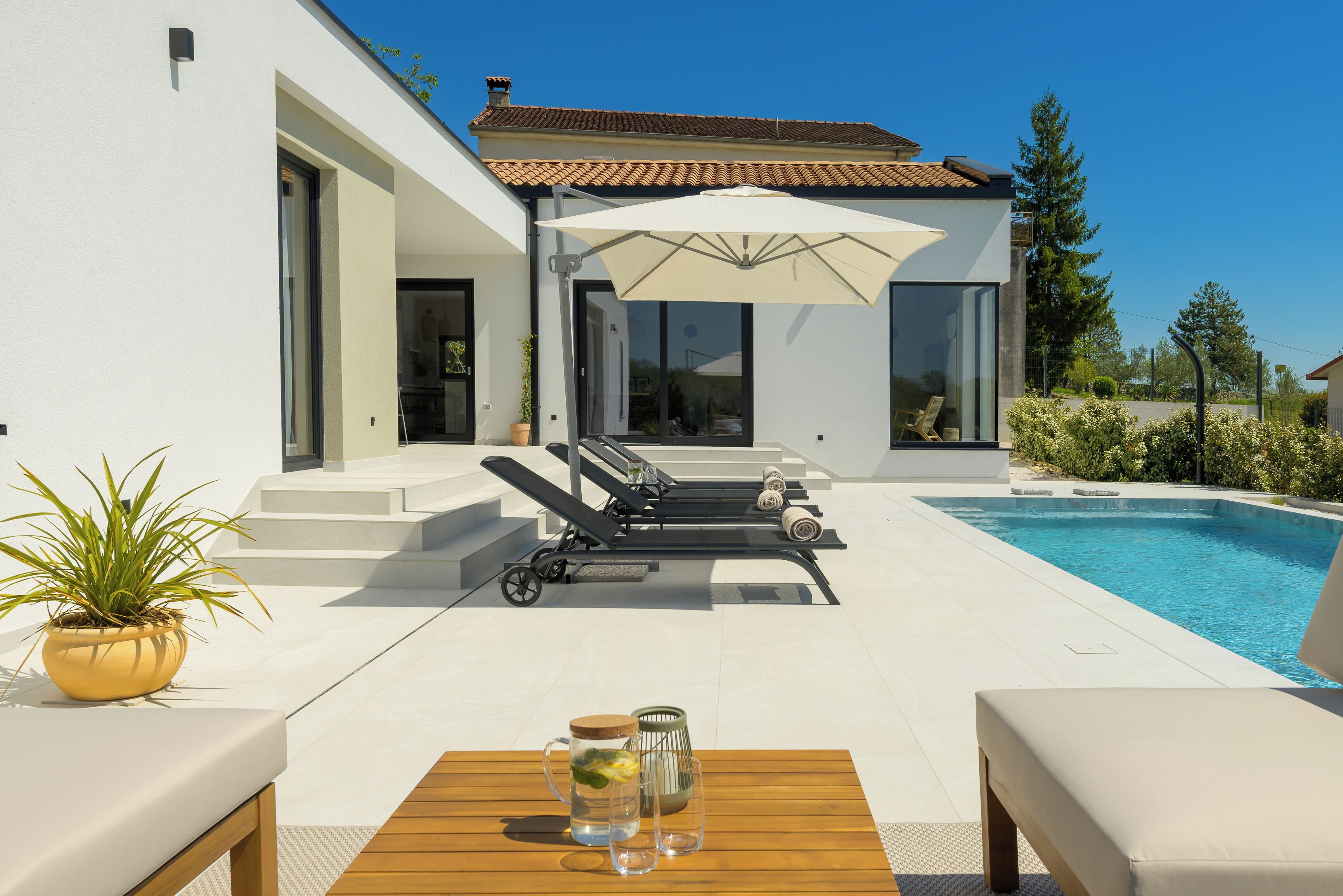Een modern huis met een zwembad, buitenmeubels en een terras.