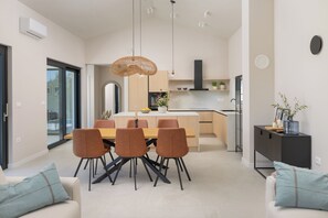 A modern kitchen with a dining area, featuring a central island, pendant lighting, and a view of the adjacent dining room. - Villa Modrić (Istria - Pazin) (Pazin)