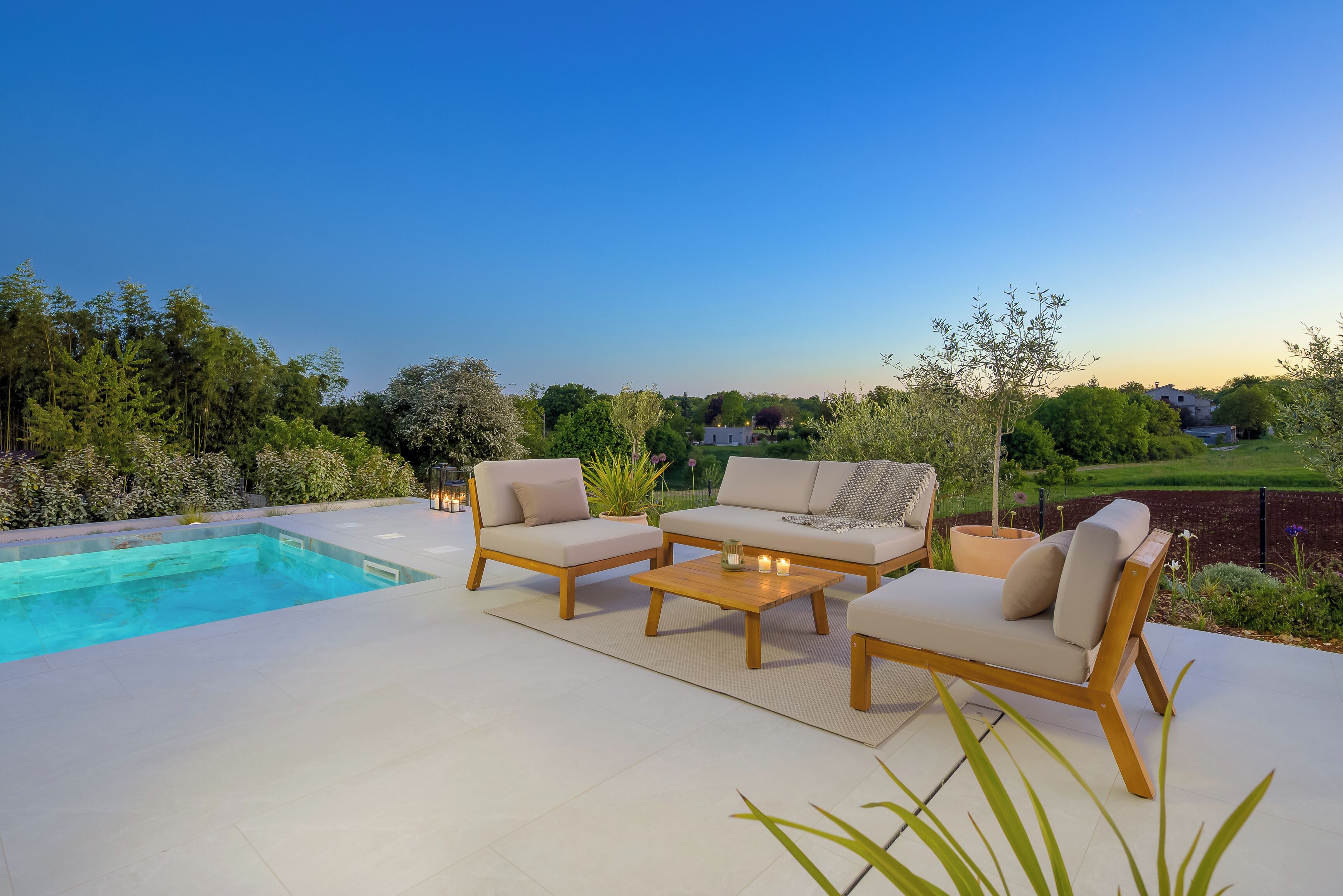 A poolside area with a sofa set, a coffee table, and a pool.