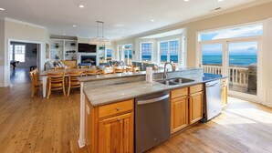 A spacious kitchen with wooden cabinets, a stainless steel dishwasher, and a large island with a sink. - Dmanfish - Oceanfront 9 BR w/pool (Virginia Beach)