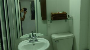 Et badeværelse med hvid vask, toilet og brusekabine i glas.