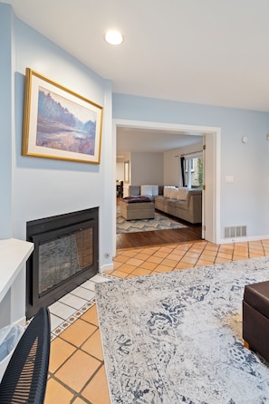 A living room with a fireplace, a large rug, and a painting on the wall.